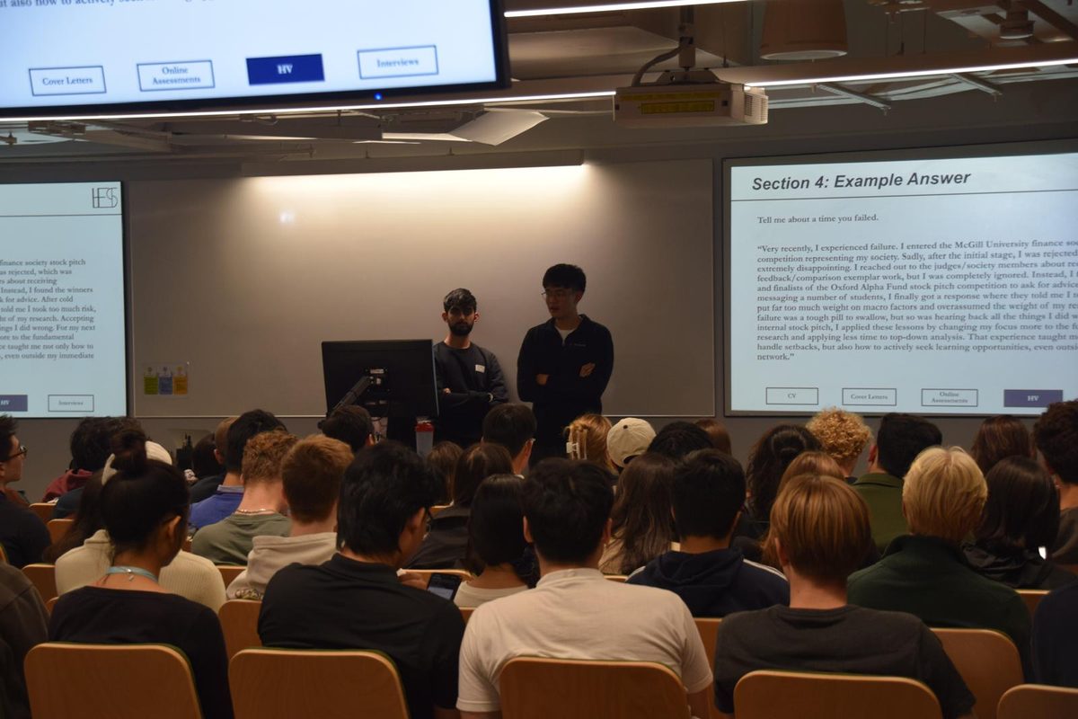 Two members present an application prep session to a full UCL lecture theatre, with slides on CVs, cover letters, online assessments and interviews.