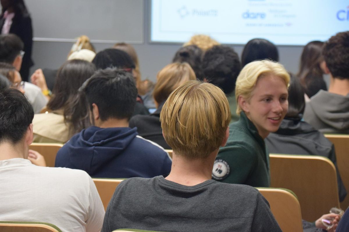 Members chatting in a packed lecture theatre at a society event.